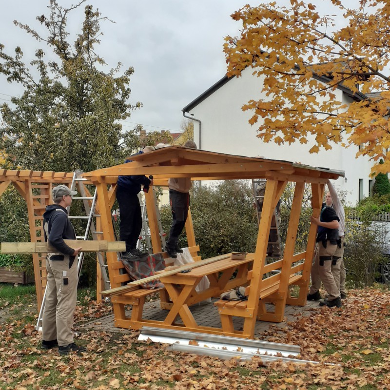 Auszubildende und Ausbilder bauen Sitzlaube