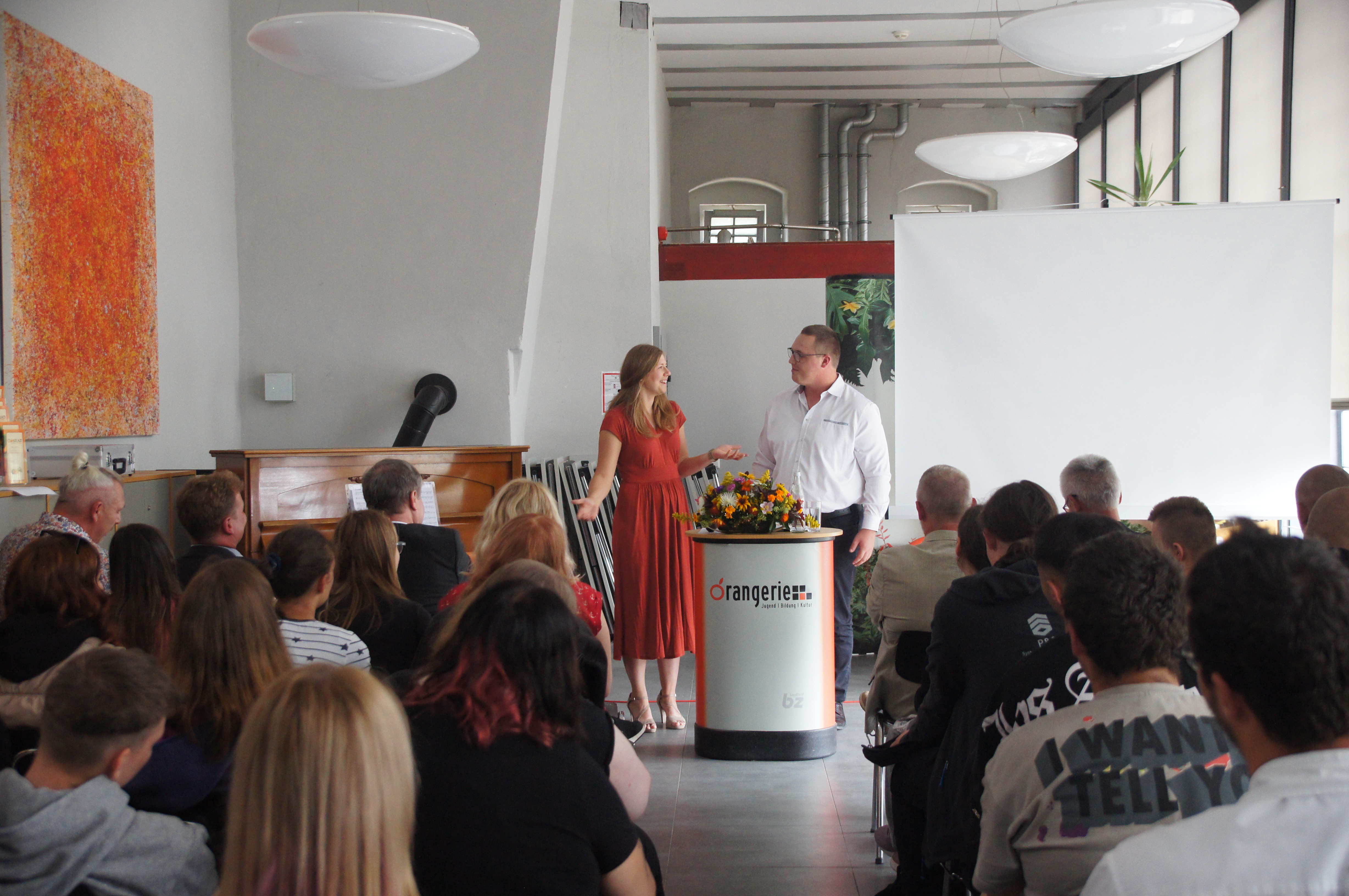 Mitarbeiterin überreicht Glückwünsche an die Gäste am Messestand